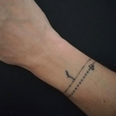 Tattoo op een pols met lijnen en een abstracte vorm.